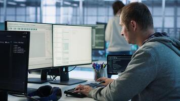 Engineer starting job shift in server hub used for processing vast amounts of data. IT programmer arriving at work in data center, sitting at PC desk, typing on keyboard, camera A photo