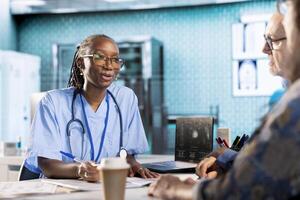 African american assistant and patients engage in medical checkup with healthcare records and x ray text results files to find accurate treatment for wellness and recovery. Healthcare practices. photo