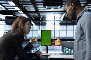 Programmers in data center brainstorming, using mockup tablet, observing analytics, reviewing equipment health. Team of server hub IT specialist use isolated screen device, adjusting system parameters photo
