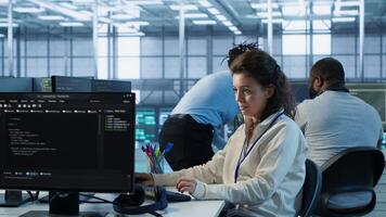 Upbeat computer scientist working in high tech server hub capable of processing vast amounts of data. Smiling woman at PC typing on keyboard, updating servers controlling network resources, camera A photo