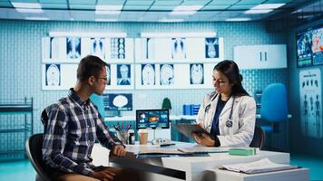 General practitioner consulting patient and reviewing x ray test results, utilizing technology for analysis and care management in a medical environment. Healthcare provider. Camera B. photo