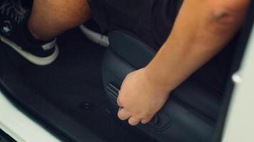 Close up of man in car pushing driver front seat forward using electric buttons. Person inside automobile moving vehicle chair closer to steering wheel using adjustment knobs photo