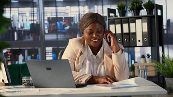 African american general manager answers smartphone call to discuss performance metrics, focusing on business development project. Director multitasking daily operations and analytics. Camera A. photo