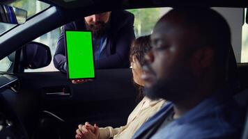 Car salesperson showing vehicle final price on isolated screen tablet to clients after finishing test drive. Dealership agent showing automobile catalog to customers on chroma key device, camera B photo