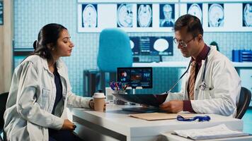 Specialist and patient discussing diagnostic results in a modern medical office, establishing advanced technology to present x ray imaging results and MRI scans. Health care management. Camera A. photo