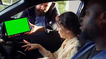 Showroom salesman showing car brochure and price list on green screen tablet to clients after they finished test drive. Dealership agent showing vehicle catalog to customers on mockup device, camera B photo