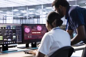 African american engineer in server hub helped by manager to investigate breach alerts, working to protect equipment from hacker. Employee requesting aid from supervisor to mitigate security risks photo