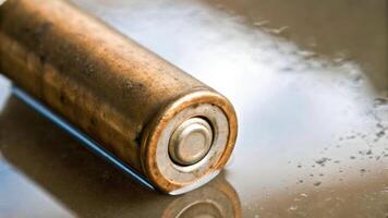 Corroded aa battery in water puddle metal surface closeup photography highlighting danger with wet environment photo