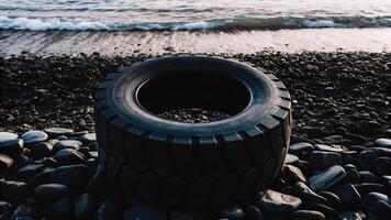 Tire on rocky beach with gentle waves conceptual image of nature calm environment and serenity photo