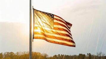 Flag waving under rainstorm at sunset capturing wet fabric illuminated by warm light and sparkling raindrops photo