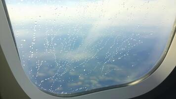 Raindrops on airplane window with a view of the blue sky and cloudscape photo
