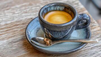 Close-Up of Rich Espresso Coffee in Artisan Ceramic Cup on Wooden Table Surface with Silver Spoon photo