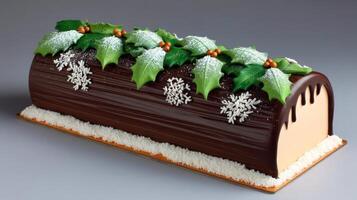 Decadent Chocolate Yule Log Cake Decorated with Holly Leaves and Snowflakes on a Gray Background photo