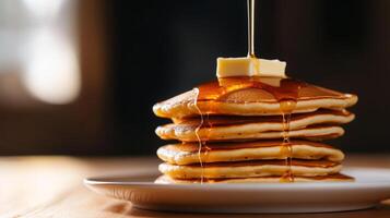 A stack of pancakes with syrup being poured on top photo