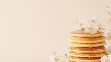 A tall stack of pancakes with syrup and flowers photo