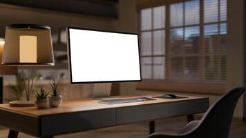 A computer placed on a hardwood desk in a cozy office at night with a warm light from the table lamp photo