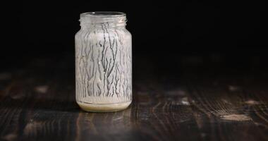 an empty glass jar with natural yogurt on the table photo