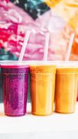 Colorful trio of refreshing summer smoothies with straw in vibrant pink, orange, and yellow photo