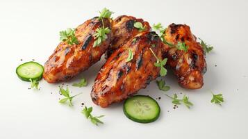 Grilled chicken wings with fresh herbs and cucumber slices on white background photo