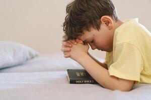 A boy with folded hands in front of him, he prays in his room. photo