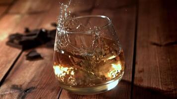 Ice falls into a glass of whiskey. Filmed on a high-speed camera at 1000 fps. High quality FullHD footage video