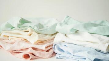 A pile of folded white and pastel colored clothes photo
