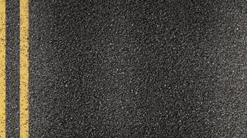 Close-up of asphalt road texture with yellow center lines for transportation and infrastructure themes photo