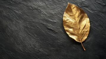 Golden leaf on dark slate stone surface representing elegance and nature concept photo