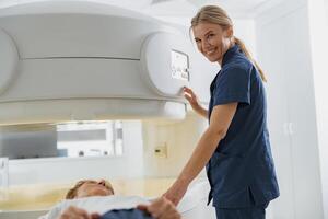 Radiologist controls MRI or CT or PET Scan with patient undergoing procedure and looking camera photo