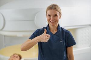 Radiologist showing thumbs up standing on background of MRI or CT Scan with patient on procedure photo