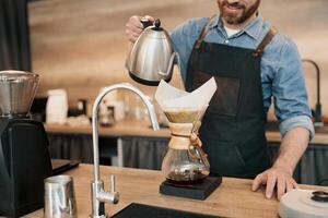Close up of Barista pouring water on coffee ground with filter photo
