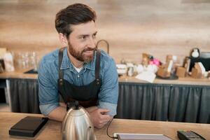 Smiling barista talking with client while standing behind a counter photo