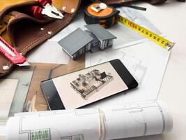 Architectural model on desk with smartphone, drawing technical tools and blueprints. Architecture, building, construction and real estate business. photo