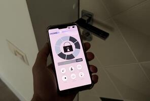 man controls smart home devices using app for mobile phone on background of businessman's work table, interior of home office. concept of digitalization. a mockup with hand holding phone. photo