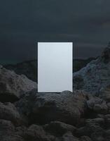 mockup of an A4 paper standing on top of rocks at night, a white blank poster, minimalistic with a very dark sky sharp focus. photo