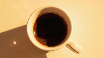 A cup of coffee is shown in the sunlight photo