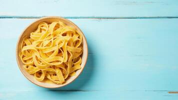 Italian pasta in a bowl on a blue wooden table top view photo