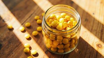 A glass jar filled with yellow candies on a wooden table photo