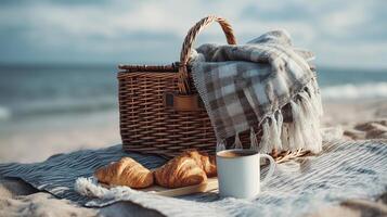 Beach picnic with croissants, coffee, and blanket under cloudy sky concept photo