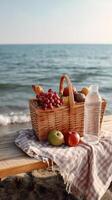 Picnic basket with fruits on a beach bench near the ocean at sunset photo