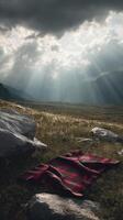 Red tartan blanket on grassy field under dramatic cloudy sky with sun rays photo