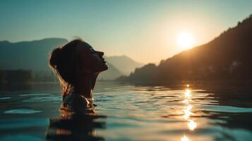 Silhouette of woman in lake during sunrise with mountains, peaceful and serene photo