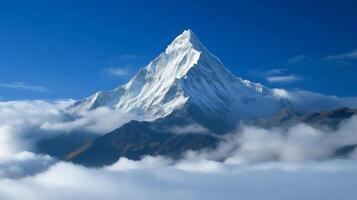 Majestic snow-capped mountain peak emerging from clouds under blue sky photo