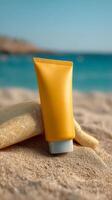 Yellow sunscreen tube on sandy beach with blue sea and sky in background photo