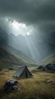 Solitary tent in a misty mountain valley beneath dramatic clouds, conceptual landscape photo