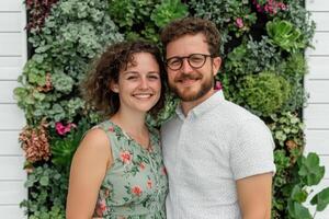 A Happy Couple Posing in Front of a Vibrant Plant Wall photo