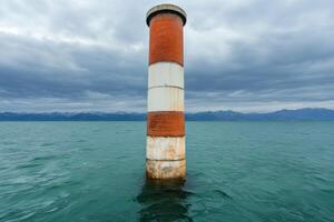 Striking Red and White Tower on a Serene Lake, Majestic Mountain View photo