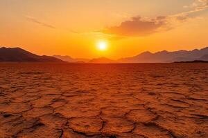 A breathtaking sunset over a cracked desert landscape. Dramatic colors paint the sky and mountains. A vast and empty expanse of dry land. photo