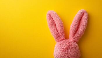 Pink bunny ears on bright bg. Soft pink bunny ears appear playfully against a vibrant yellow background, creating a cheerful and inviting atmosphere. photo