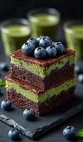 Delicious chocolate berry dessert layers. Layers of rich chocolate cake with vibrant green filling and fresh blueberries on top create a tempting dessert. photo